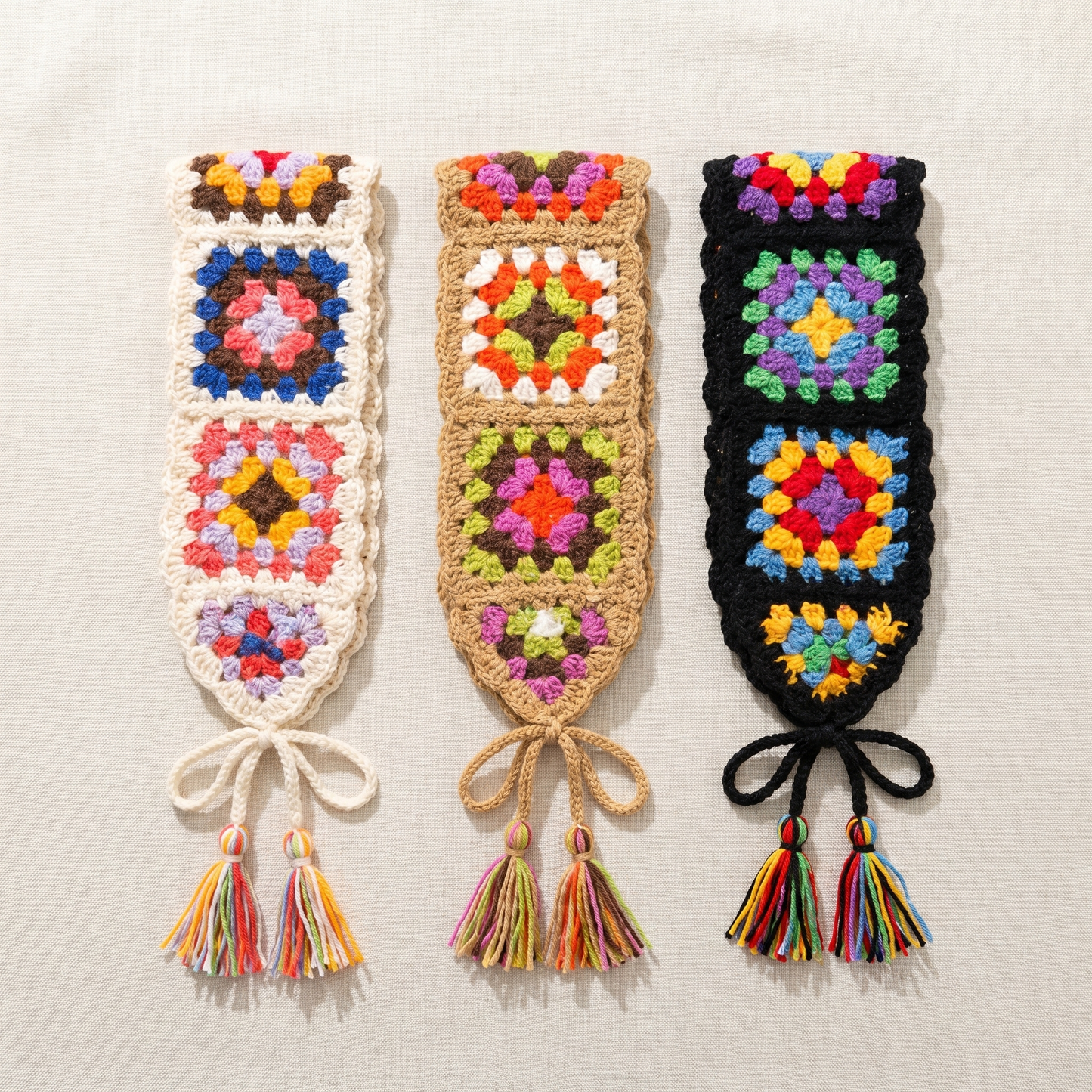 Set of three hand-crocheted granny-square headbands in cream, camel and black, flat-lay