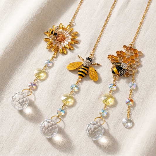 Set of three bee, honeycomb and sunflower crystal light-catchers arranged on cream linen