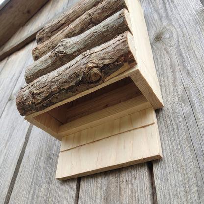 Low-angle view showing the open-bottom entry and landing board where bats climb in