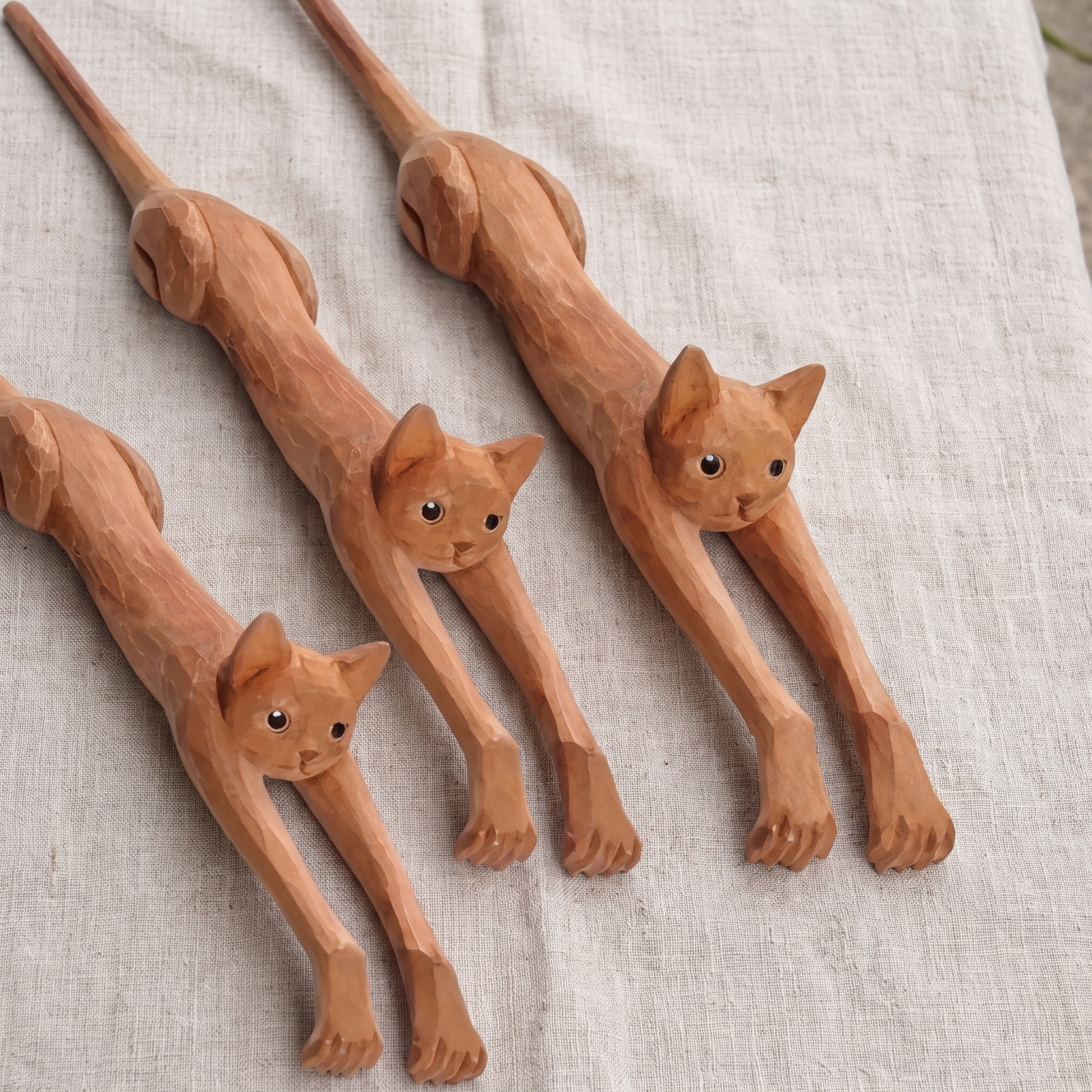 Three hand-carved cat back scratchers on linen showing slight handmade variation
