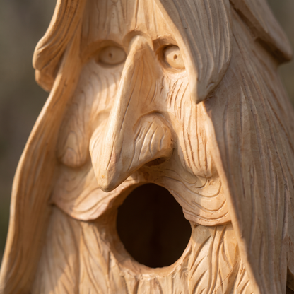 Extreme close-up of the hand-carved wood spirit face showing grain and tool marks