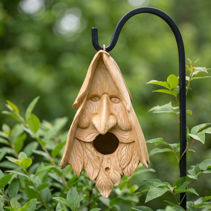 Wood spirit birdhouse hanging from a wrought-iron garden hook among green foliage
