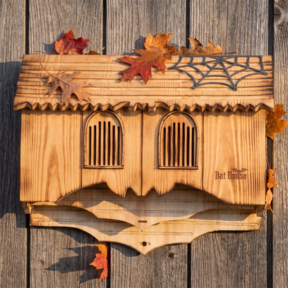 Gothic bat house mounted on a weathered barn wall with autumn leaves